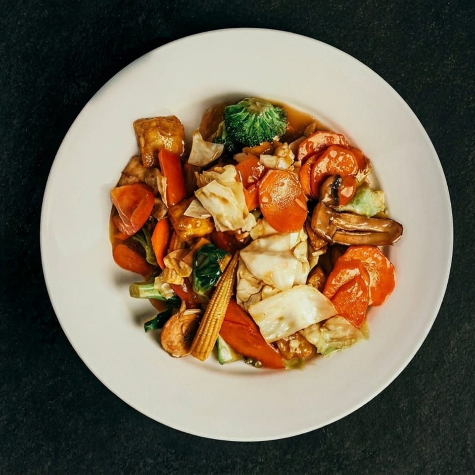 A white plate filled with colorful stir-fried vegetables and tofu in a savory sauce.