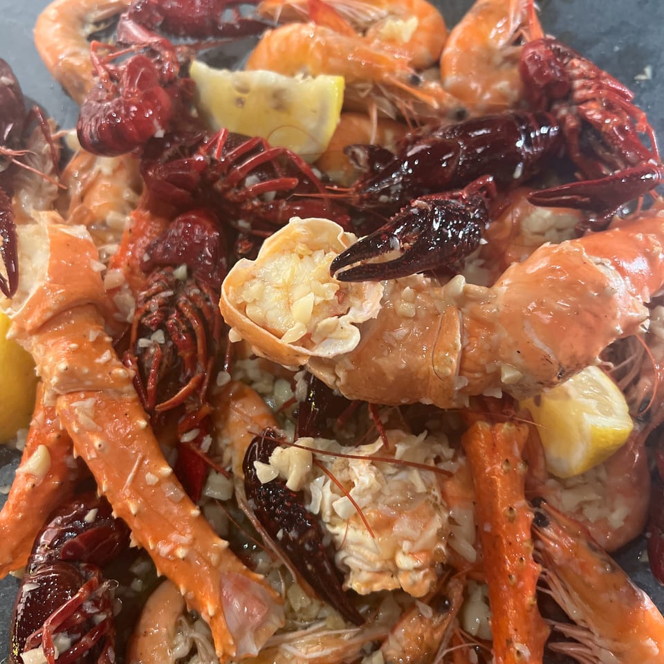 Platter of seasoned shrimp, crawfish, and crab legs with lemon wedges.